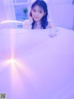 A young woman laying on a bed talking on a cell phone.