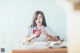 A woman sitting at a desk with a red bow tie.