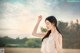 A woman in a white top standing in a field.