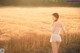 A woman in a white dress standing in a field.