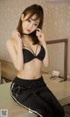 A woman in a black bra top and black pants sitting on a table.