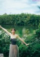 A woman in a gray dress standing in front of a lake.