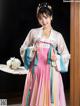 A woman in a pink and blue hanbok is posing for a picture.