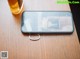 A cell phone sitting on top of a wooden table next to a glass of beer.