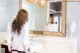 A woman standing in front of a mirror in a bathroom.