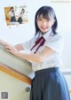 A woman in a school uniform leaning against a railing.